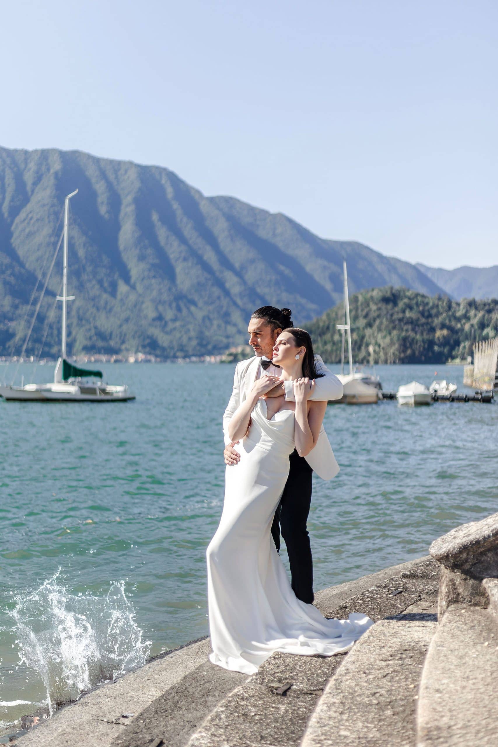 Bride and groom standing on stairs next to lake